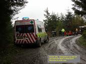 A Forest Rally. competition car has left the road and is down a steep bank. Lace crew standing by whilst recovery is under way.